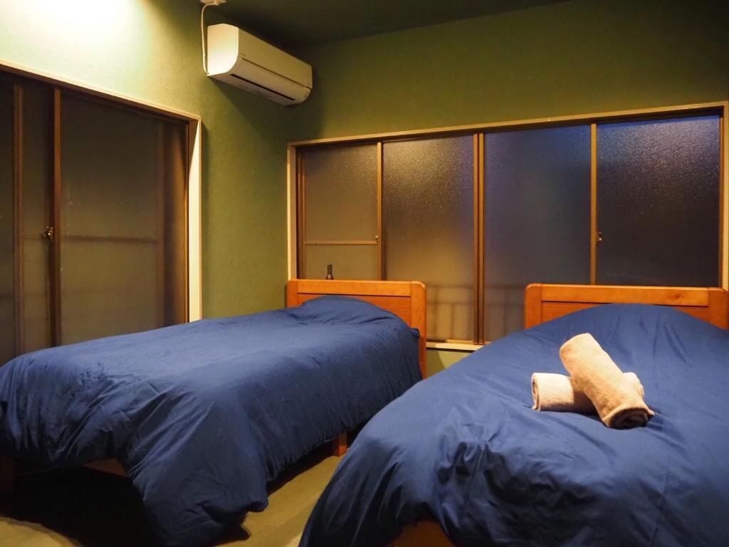 A room with two beds, a wardrobe, and a window.