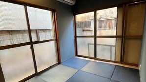 A room with tatami flooring, sliding doors, and an air conditioning unit.