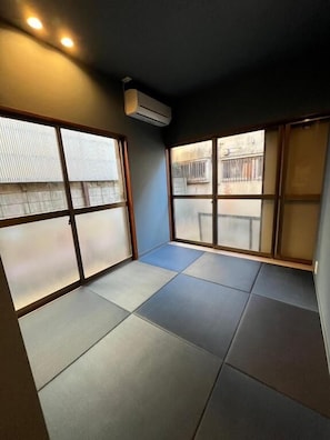 A room with tatami flooring, sliding doors, and an air conditioning unit. - BED&BAR MIDUKI (Tokyo)