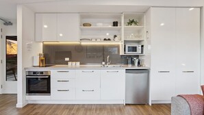 Uma cozinha moderna com armários brancos, forno embutido, micro-ondas e máquina de lavar louça.