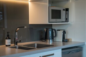 A modern kitchen with a built-in microwave, a kettle, and a coffee maker. - Queenstown Quarters - Residence IV (Queenstown)