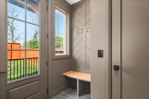 A room with a window, a bench, and a wall-mounted light switch.
