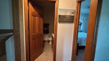 A hallway leading to a bathroom with a toilet, a sink, and a mirror.