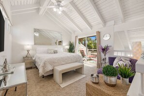 A bedroom with a bed, bench, bedside table, mirror, and a view of the outdoors. - Palm Springs Golf Condo with Pools, Spas, Pickleball, Fire Pit and Mountain Views (Palm Springs)