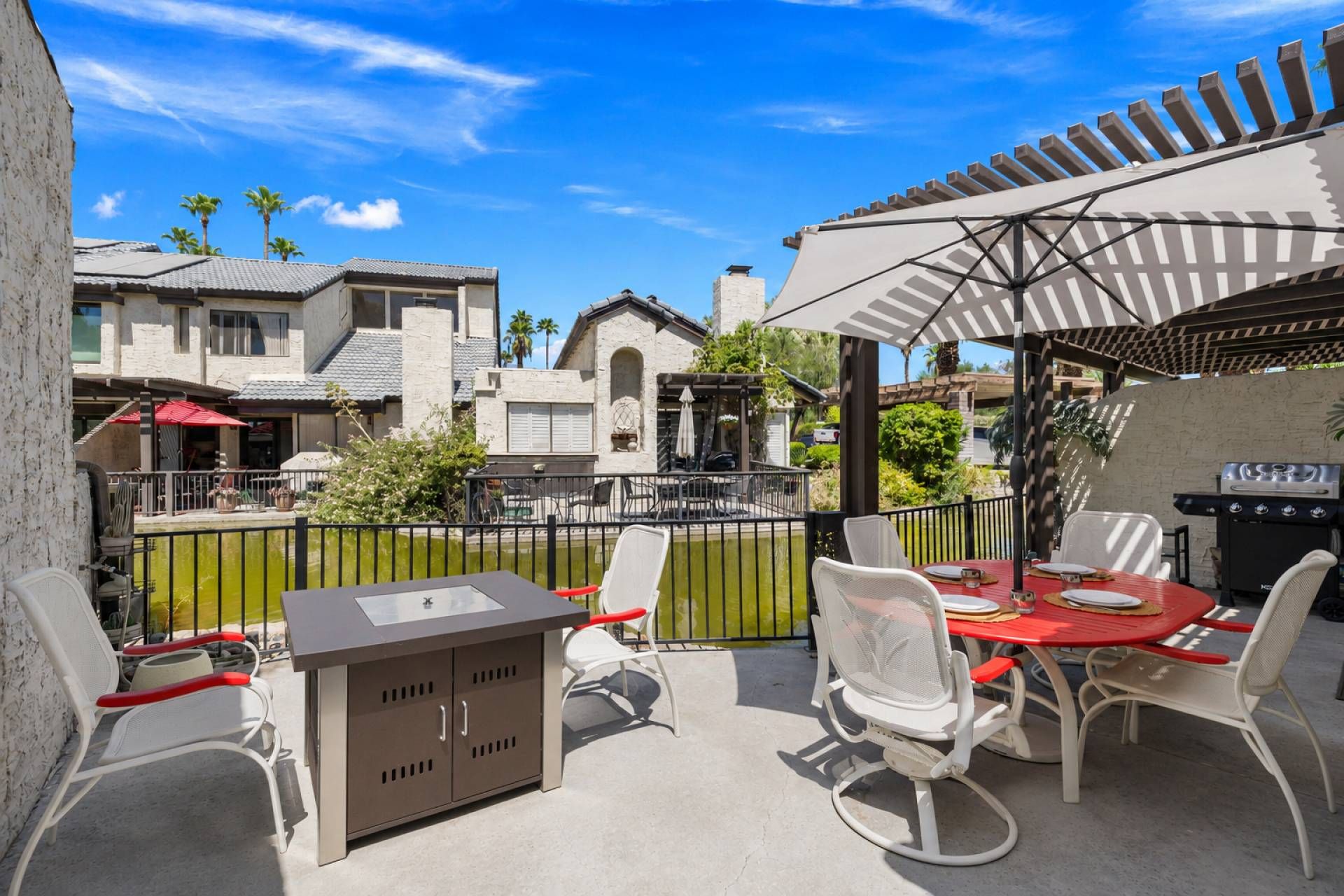 An outdoor patio with a grill, chairs, and a table set up for dining.