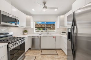 A modern kitchen with stainless steel appliances, a dishwasher, and a window with a view of the outside. - Palm Springs Golf Condo with Pools, Spas, Pickleball, Fire Pit and Mountain Views (Palm Springs)