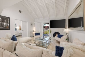 Ein Wohnzimmer mit hoher Decke, einem Kamin und einem an der Wand befestigten Fernseher.