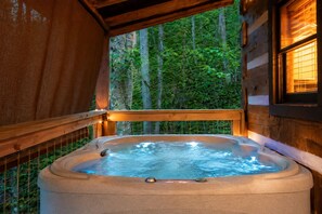 Ein Whirlpool in einer Holzhütte mit Blick auf einen Wald.