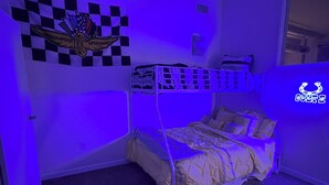 Una habitación con una litera, un adorno de pared a cuadros y una cama con almohada.
