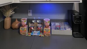 Una cocina con armarios blancos, una cafetera y varios alimentos en la encimera.