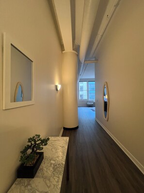 A hallway with a marble bench, a potted plant, and a large pillar. - Downtown Indianapolis with Direct Convention Center Access + Parking (Indianapolis)
