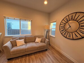 A living room with a large wall clock, a sofa, and two windows. - The Point Retreat, Theater, Firepit, Near I-15 (Bluffdale)