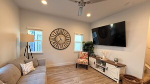 A living room with a sofa, a clock, a television, and a ceiling fan. - The Point Retreat, Theater, Firepit, Near I-15 (Bluffdale)