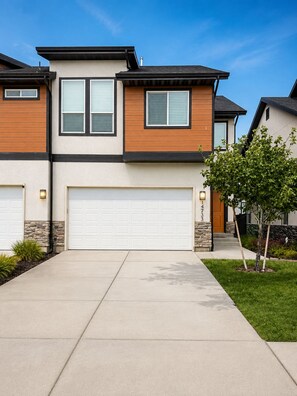 A two-story house with a garage, a stone accent wall, and a well-maintained lawn. - The Point Retreat, Theater, Firepit, Near I-15 (Bluffdale)