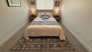 A bedroom with a bed, two bedside tables, a window with blinds, a rug, and two wall-mounted lamps. - The Point Retreat, Theater, Firepit, Near I-15 (Bluffdale)