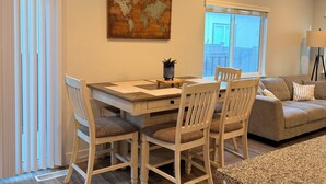 A dining area with a wooden table and chairs, a world map artwork, and a view of the outdoors through a sliding door. - The Point Retreat, Theater, Firepit, Near I-15 (Bluffdale)