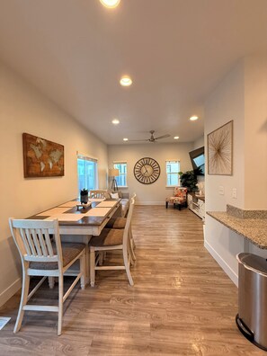 A spacious dining area with a long table, chairs, and a large wall clock. - The Point Retreat, Theater, Firepit, Near I-15 (Bluffdale)
