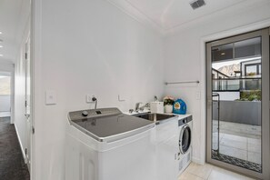 Ein kleiner Waschraum mit Waschmaschine, Spüle und großem Fenster.
