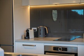 Eine moderne Küche mit eingebautem Backofen, einer Kaffeemaschine und einem Wasserkocher.