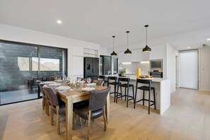 Een moderne keuken met een centraal eiland, een eethoek met houten tafel en stoelen, en hanglampen.