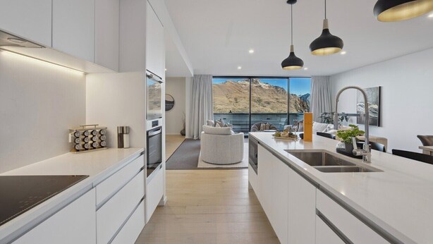 Een moderne keuken met een centraal eiland, een eetgedeelte met uitzicht en een groot raam dat uitkijkt op een bergachtig landschap.