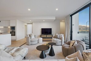 A modern living room with a sofa set, a coffee table, and a television. - Remarkable New Home on the Hill (Queenstown)