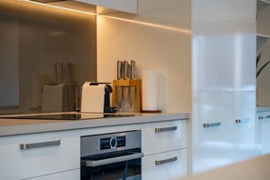 A modern kitchen with a built-in oven, a coffee machine, and a knife block. - Queenstown Quarters - Residence III (Queenstown)
