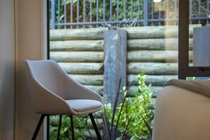 Una silla junto a una ventana con vista a una cerca de madera y follaje.