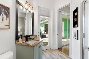A bathroom with a granite countertop, a large mirror, and a light fixture above the mirror. - Min from Naples in Beautiful Brendan Cove w/Private Pool and Covered Courtyard (Bonita Springs)
