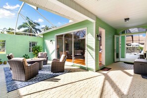 A covered outdoor patio with wicker furniture, a fire pit, and a view of the backyard. - Min from Naples in Beautiful Brendan Cove w/Private Pool and Covered Courtyard (Bonita Springs)