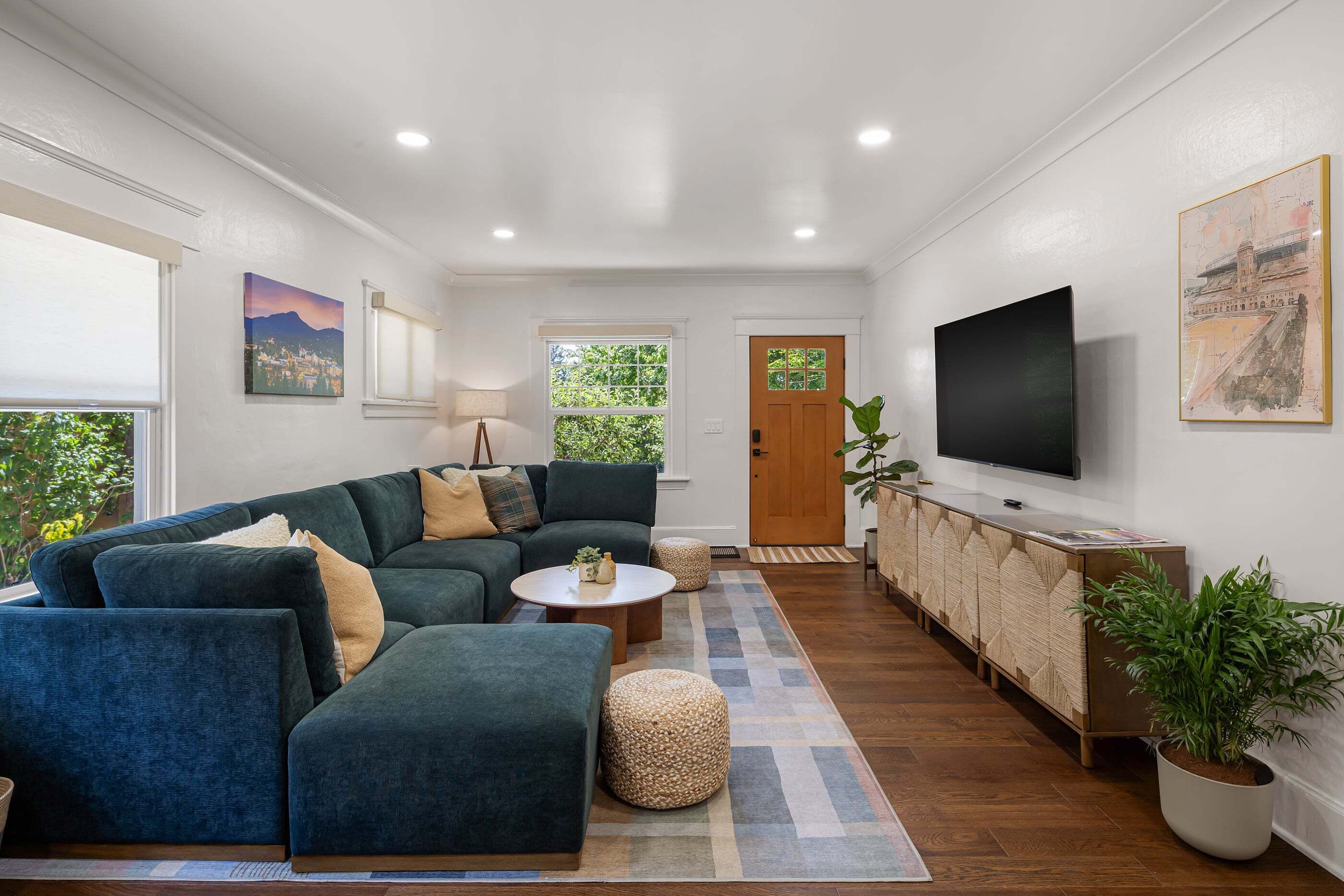 Una sala de estar moderna con un sofá modular, un televisor de pantalla plana y un ventanal grande.