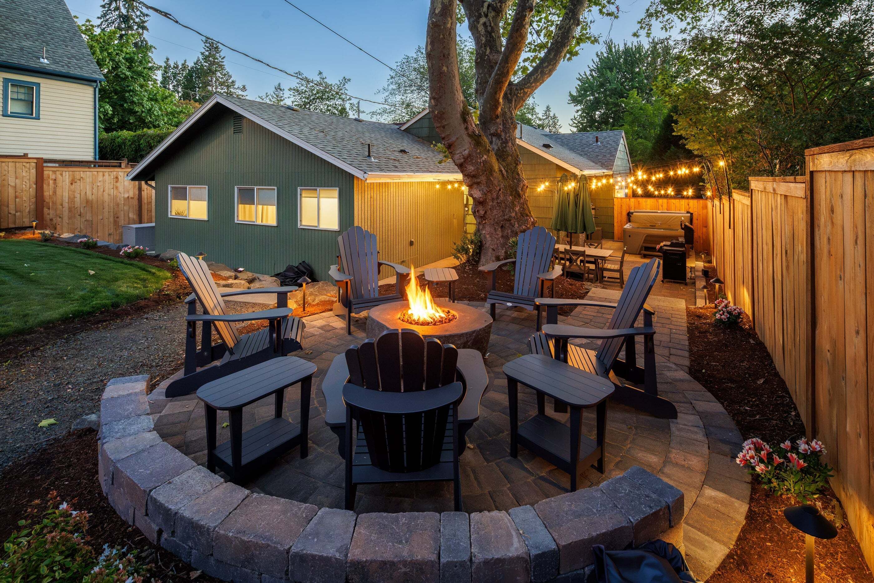 A backyard with a fire pit, outdoor seating, and a wooden deck.