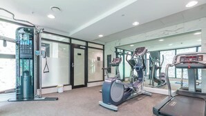 Ett gym med träningsutrustning, en vägg med speglar och en dörr som leder till ett annat rum.