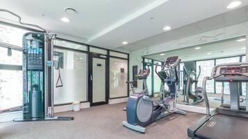 A gym with exercise equipment, a mirrored wall, and a door leading to another room.