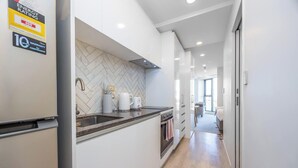 A modern kitchen with white cabinetry, a herringbone backsplash, and a built-in oven.
