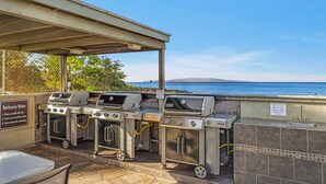 An outdoor barbecue area with multiple grills and a hand washing station, overlooking a scenic view. - Charming Tropical 2BR Condo in Kihei (Kihei)
