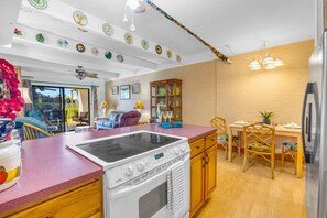 Eine Küche mit Herd, einem Esstisch mit Stühlen und einem Kühlschrank.