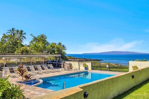 Ein Pool mit Liegestühlen, ein Barbereich und Blick aufs Meer.