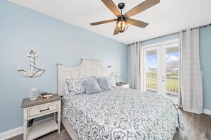 A bedroom with a bed, a nightstand, a ceiling fan, and a view through a window. - Eden's Waters: Gulf Front; Htd Prv Pool; Golf; Arcade; Lux Services; Strlnk; (Baldwin County)