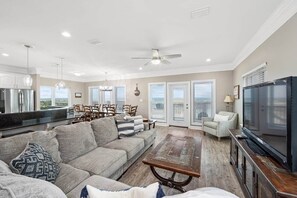 A spacious living room with a sofa, coffee table, and television. - Eden's Waters: Gulf Front; Htd Prv Pool; Golf; Arcade; Lux Services; Strlnk; (Baldwin County)