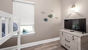 Een kamer met een stapelbed, een dressoir, een flatscreen televisie en wanddecoraties.