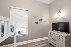 Ein Zimmer mit Etagenbett, Kommode, Flachbildfernseher und Wanddekorationen.
