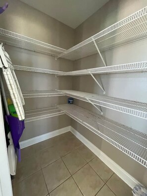 Ein Teil eines Raumes mit weißen Regaleinheiten aus Draht vor einer beige gefärbten Wand.