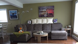 A living room with a grey sofa, a coffee table, and a large rug.