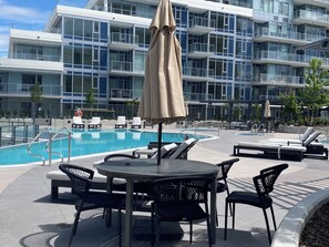 A pool area with lounge chairs, a table, and umbrellas. - Aqua Waterfront Resort (Kelowna)