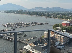 A marina with boats docked, a pier extending into the water, and buildings in the background. - Aqua Waterfront Resort (Kelowna)