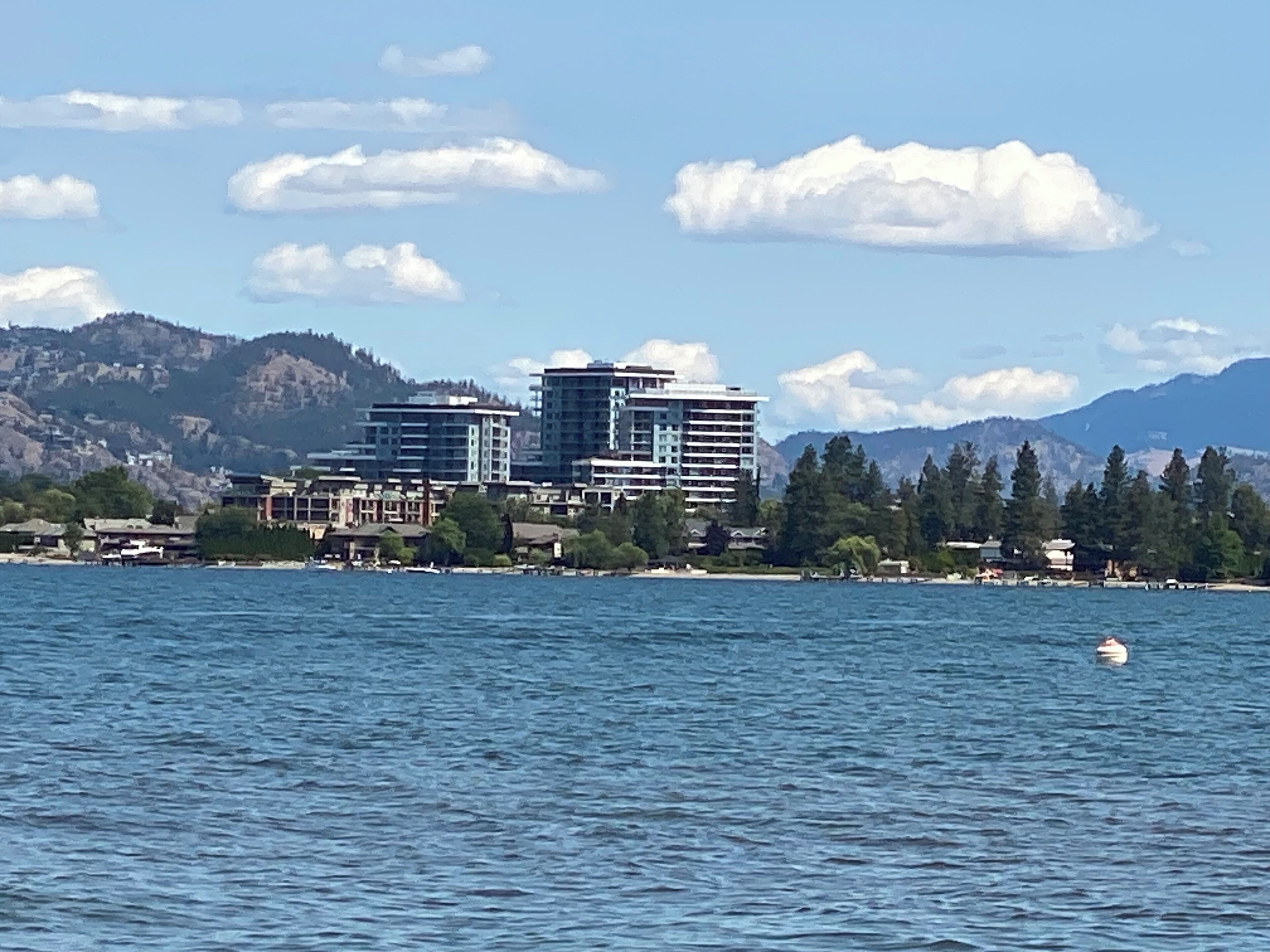 A waterfront hotel with multiple buildings, a view of the water, and a mountainous backdrop.