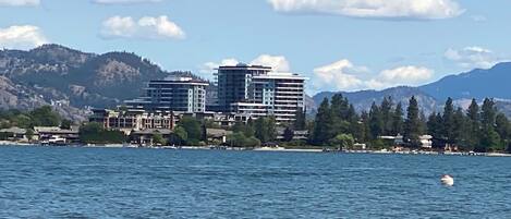A waterfront hotel with multiple buildings, a view of the water, and a mountainous backdrop.