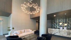 Eine moderne Lobby mit einem weißen Sofa, schwarzen Sesseln, einem Glastisch und einer außergewöhnlichen Leuchte.