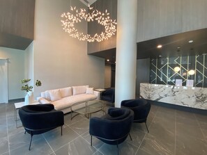 A modern lobby with a white sofa, black armchairs, a glass coffee table, and a unique light fixture. - Aqua Waterfront Resort (Kelowna)